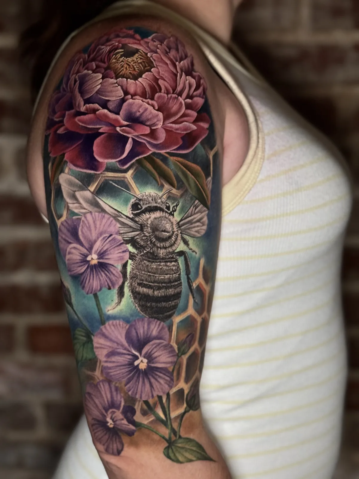 Color realism half sleeve with a peony, pansies, a bee and honeycomb