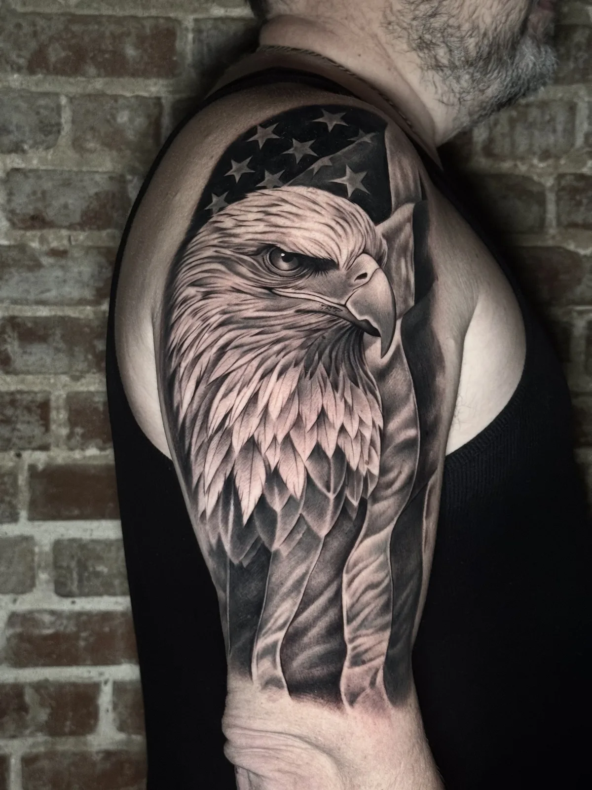 Black and grey half sleeve of a bald eagle in front of the American flag