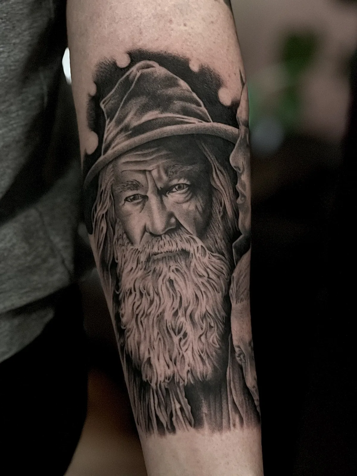 Black and grey realism forearm tattoo of an old wizard with a long beard