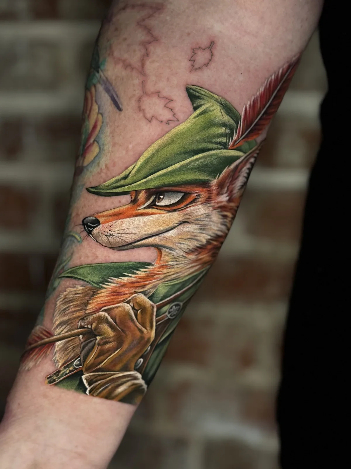 Color forearm tattoo of a fox dressed as Robin Hood