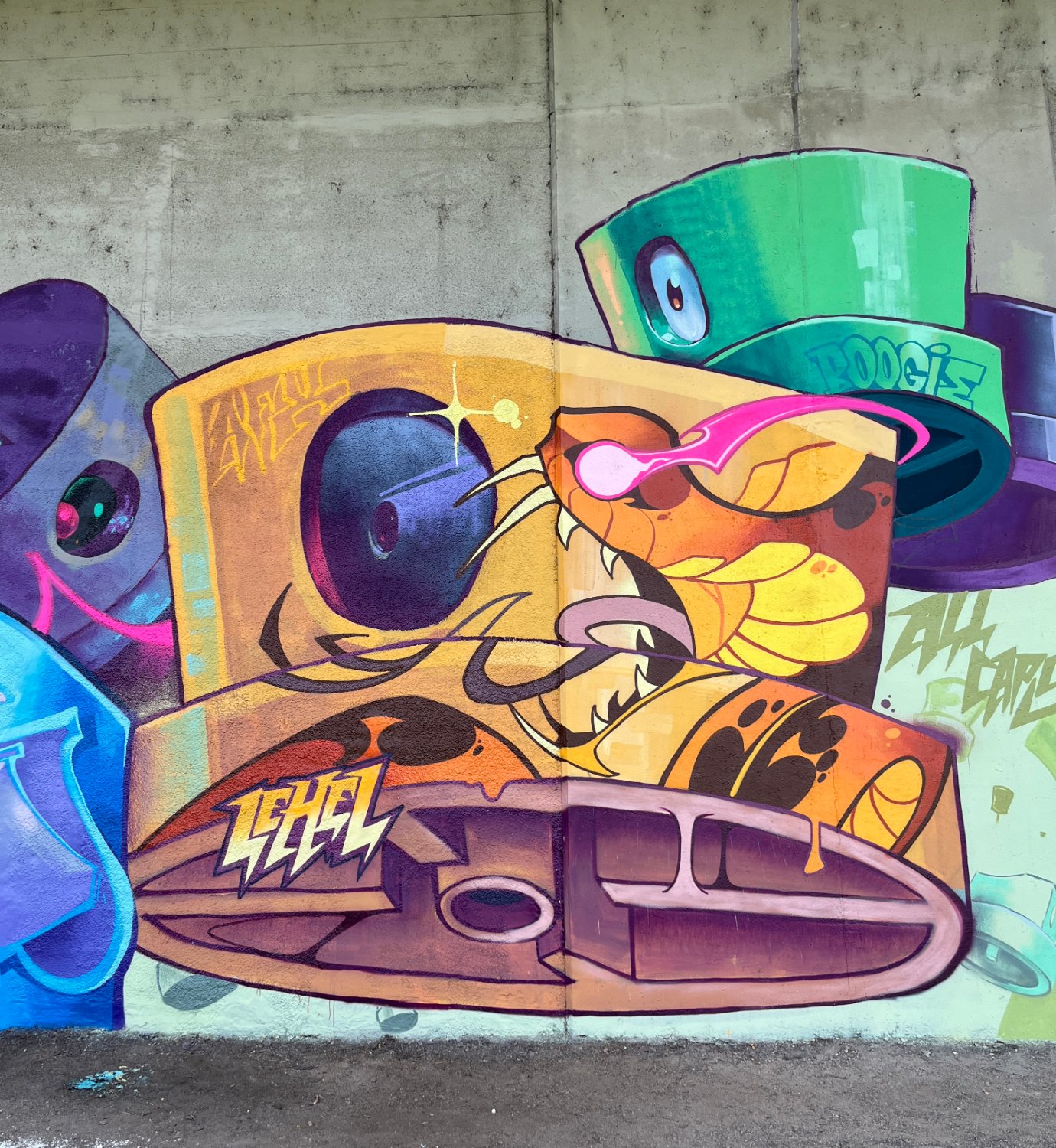 A graffiti mural on rough concrete featuring a cartoonish yellow snake with pink glowing eyes as the central figure, a large bright-green top hat character with the word BOOGIE above it, angular blue and purple lettering to the left, and the stylised word LEBEL in yellow and white below the snake's