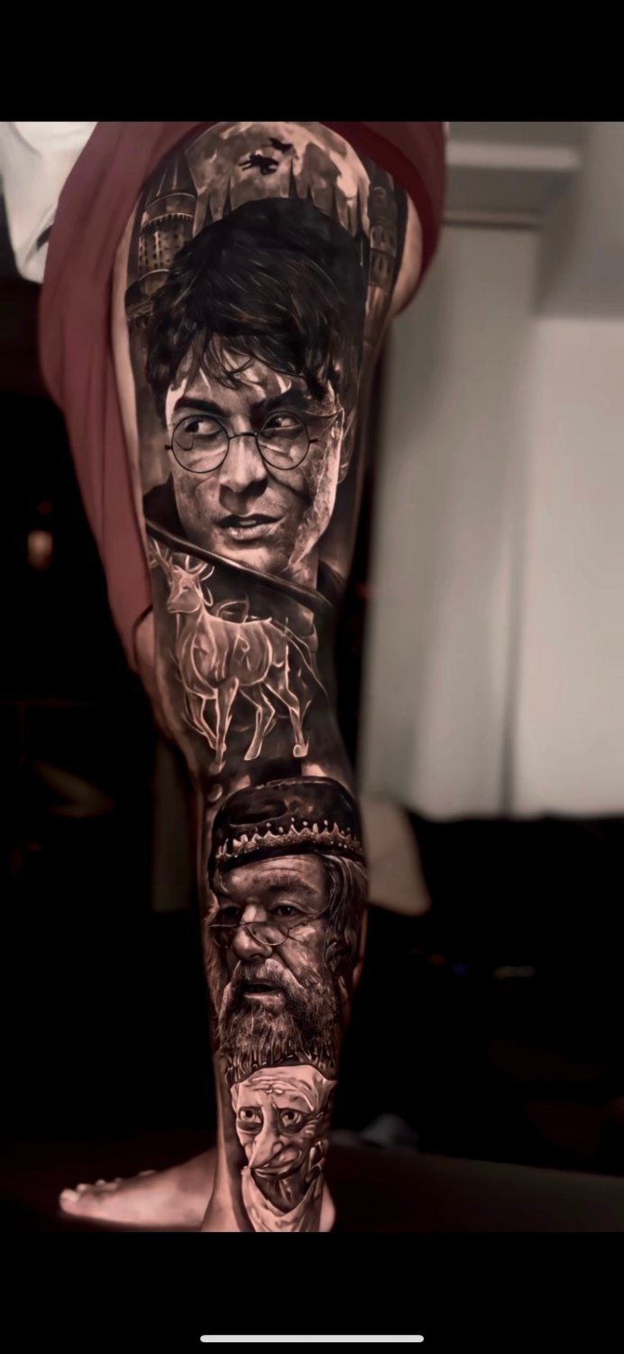 A black and grey realism tattoo covering a large portion of a leg, showing Harry Potter's portrait with round glasses and a stag Patronus at the top, Hogwarts Castle in the background, Dumbledore's bearded face with ornate hat in the middle section, and a third gaunt character below, all rendered in